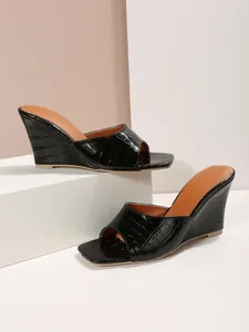 Vue détaillée latérale de sandales compensées noires élégantes en cuir à motif crocodile