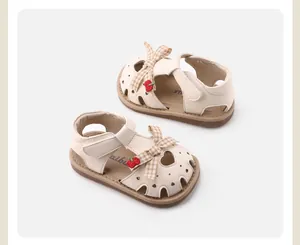 Cute cream-colored baby girl sandals featuring plaid bow and red cherry decorative details