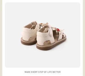 Rear view detail of cream baby girl soft sole sandals with bow and cherry accents