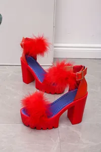 Close-up of red chunky heel sandals featuring vibrant faux fur straps and platform sole.