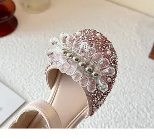 Detailed view of the sparkling crystal flower and pearl accents on pink girls' princess shoes