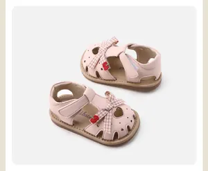 Close-up of pink baby sandals with plaid bow and cherry detail for girls.