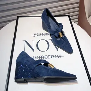 Detail view of navy blue suede Mary Jane shoes with pointed toes and rhinestone wedge heels