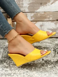 Gros plan de sandales à talons compensés jaunes pour femmes à texture crocodile