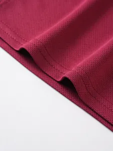 Macro detail of breathable maroon mesh fabric with durable double-stitched hem.
