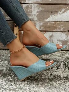 Gros plan sur la texture crocodile bleu clair de ces sandales compensées pour femmes.