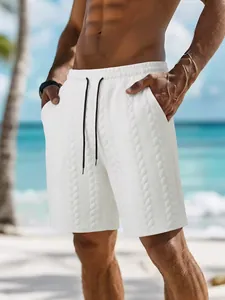 Detailansicht weißer Herrenshorts mit Jacquard-Muster und Kordelzug am sonnigen Strand.