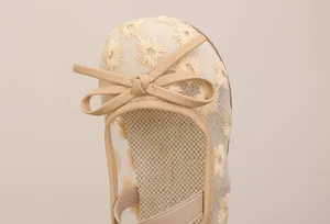 Close-up of girl's embroidered princess shoes with delicate floral patterns and bow