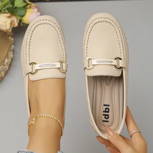Λεπτομερής άποψη των μπεζ loafers με χρυσή αγκράφα και ανάγλυφη υφή δέρματος