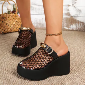 Detail van zwarte mesh sleehak sandalen met een gouden gesp en dikke plateauzool.