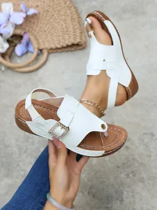 Close-up of stylish white wedge sandals with rhinestone buckle and elastic back strap