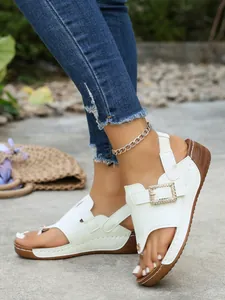 Detailed view of white wedge thong sandals featuring a sparkling rhinestone buckle.