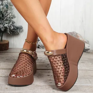 Detailopname van elegante bruine mesh sleehaksandalen met gouden gesp op houten vloer.