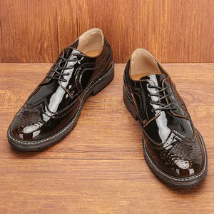 Primer plano de zapatos Brogue de charol marrón con perforaciones wingtip y cordones negros.