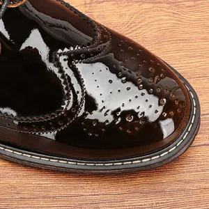 Vista detallada de los grabados brogue en zapatos de vestir de charol negro brillante para hombre