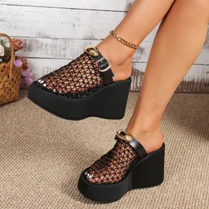 Detailweergave van zwarte platform sleehak sandalen met mesh en gouden metalen gesp