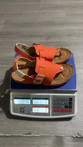 Orange wedge sandals on electronic scale showing precise product weight measurement
