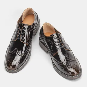 Primer plano de zapatos Oxford de hombre en charol negro con perforaciones Brogue