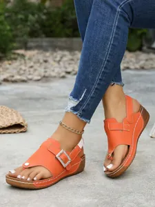 Close-up detail of women's orange thong wedge sandals featuring a stylish rhinestone buckle