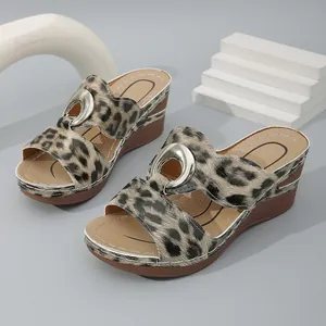 Sandales à talon compensé avec imprimé léopard et boucle métallique sur fond gris.