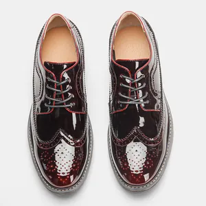 Vista superior de zapatos brogue para hombre en charol burdeos con ribetes rojos.