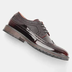 Primer plano de zapatos Brogue de hombre en charol burdeos con perforaciones de ala.
