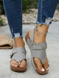 Close-up view of stylish grey wedge thong sandals featuring a sparkling rhinestone buckle