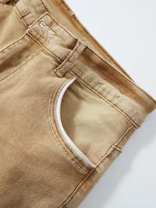 Macro detail of the front pocket on men's vintage washed brown stretch denim jeans