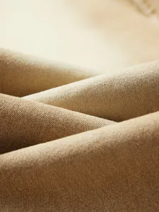 Close-up of khaki stretch denim fabric showing durable diagonal weave and texture.