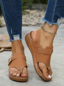 Detailed close-up of brown wedge sandals with rhinestone buckle and toe-post design
