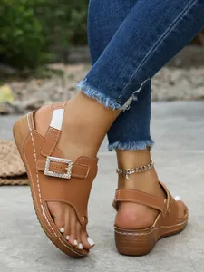 Detailed close-up of stylish tan wedge sandals featuring a sparkling rhinestone buckle