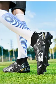 Action shot of professional high-top soccer cleats with black and white graphics on grass