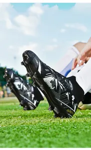 Close-up of professional high-top soccer cleats with studs on green grass field