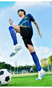 Dynamic action shot of professional high-top soccer cleats on an outdoor football field.
