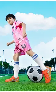 Close-up van een jongen die traint op kunstgras met oranje TF-voetbalschoenen met klittenband