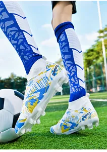 Professional high-top soccer cleats with blue and yellow patterns on a turf field