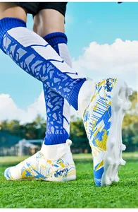 Detail of high-top soccer shoes with blue and yellow patterns on professional turf.