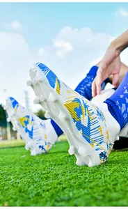 Professional high-top soccer shoes with firm ground spikes shown on green grass field