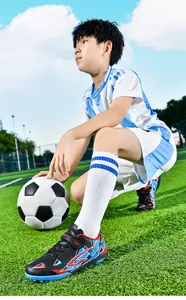Close-up van kindervoetbalschoenen met klittenbandsluiting op een kunstgrasveld