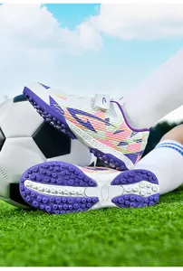 Detail van voetbalschoenen voor kinderen met klittenband en TF rubberen zolen op gras
