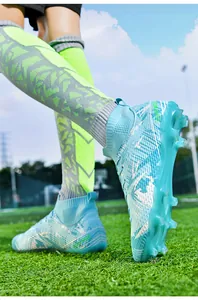 Macro view of professional light blue high-top soccer cleats with studs on pitch