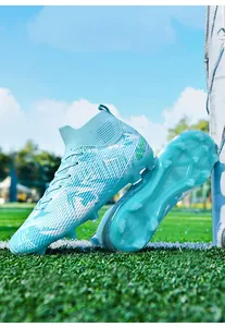 Professional high-top soccer cleats with light blue camouflage pattern on a green field