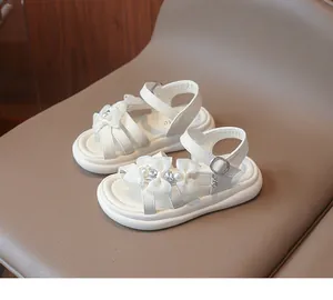 Detailed view of white girls' sandals with lace bows and pearl decorations