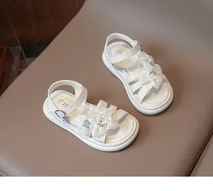 Detailed view of white girls' princess sandals with decorative bows and pearls.
