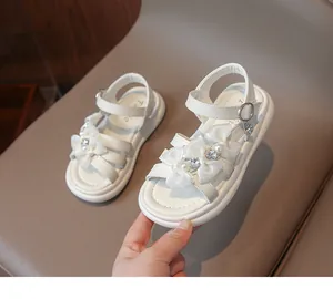 Detailed view of white girls' princess sandals featuring decorative bows and pearl accents
