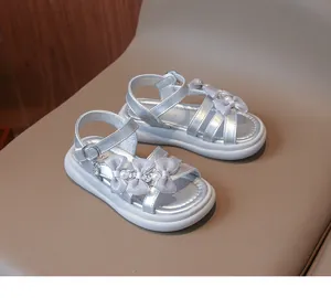 Detailed close-up of silver girls' princess sandals featuring bows, pearls and crystals.