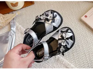 Detailansicht von silbernen Mädchen-Sandalen mit funkelnden Strasssteinen und Schleifen
