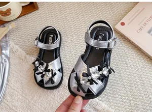 Detailansicht der silbernen Mädchensandalen mit edlen Strasssteinen und Schleifen