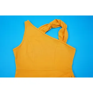 Detailed view of an elegant orange one-shoulder evening dress with twisted strap
