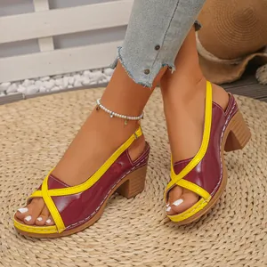 Detail van tweekleurige sandalen met blokhak en gele kruisbandjes op een geweven mat